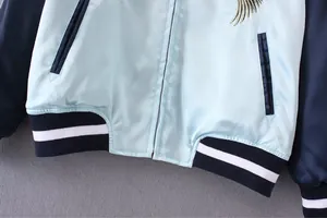 Nahaufnahme einer hellblauen Satin-Sukajan-Jacke mit geripptem Saum und Taschendetails