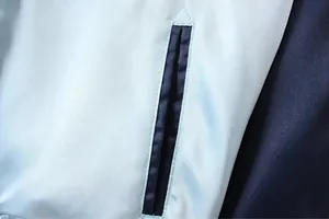 Detailgetreue Nahaufnahme der Taschennaht an einer blauen Satin-Sukajan-Baseballjacke.