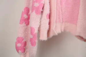 Vista detallada del suave cárdigan de punto peludo rosa con patrones de flores.