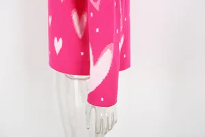 Detailed close-up shot showing the pink heart pattern and knit texture of a cozy sweater.
