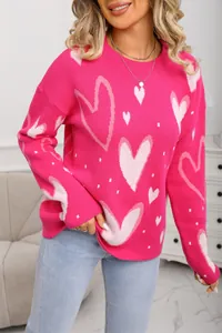 Detail of women's oversized bright pink knit sweater featuring pink heart patterns.