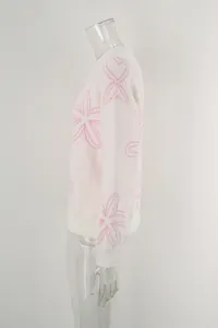 Detailed side view of a white long-sleeved knit sweater featuring pink floral prints