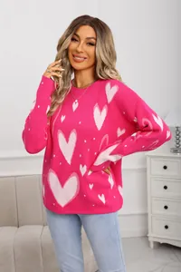 Close-up view of pink knitted sweater featuring white heart jacquard pattern