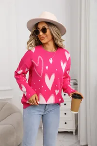 Detail of pink knitted sweater with oversized heart patterns and crew neck design