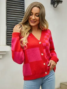 Close-up view of a stylish red and pink checkered knit cardigan on a model outdoors