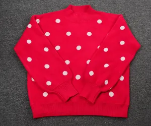 Macro view showing the detailed knit texture and white polka dot pattern of the red sweater