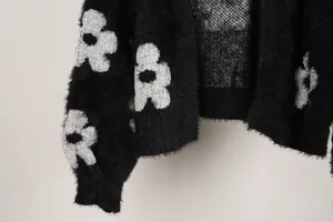 Primer plano de la textura suave y peluda y el estampado de flores blancas de un cárdigan negro