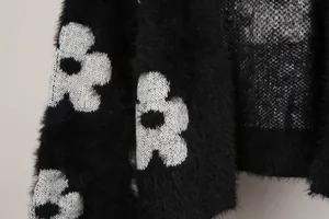 Detalle de un suave cárdigan de punto negro con textura peluda y estampado de flores blancas