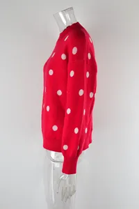 Side view of a red knit sweater with white polka dots on a clear mannequin