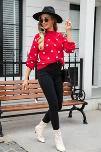 Stylish red pullover sweater featuring large white polka dots in a modern street setting
