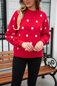 Detailed view of a stylish red knit sweater featuring bold white polka dots on a model