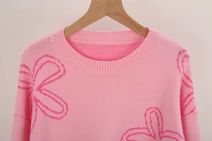 Close-up detail of a pink crew neck sweater featuring a vibrant pink floral pattern.