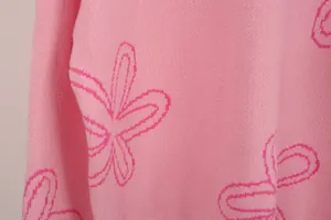 Close-up of pink knitwear sweater featuring vibrant fuchsia flower pattern detail