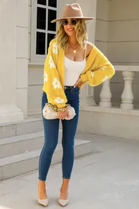Detalle de conjunto con cárdigan amarillo de flores y vaqueros pitillo en exterior.