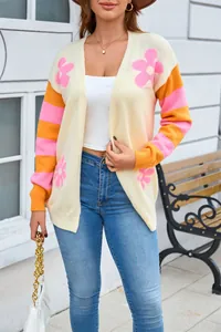Dettaglio di una donna con cardigan in maglia a fiori e maniche a righe rosa e arancioni.