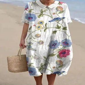 Vintage stijl lange jurk met bloemenprint en witte Peter Pan-kraag op het strand.