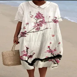Detail van een witte jurk met poppenkraag en roze kersenbloesemprint op het strand