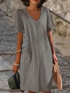 Grey cotton linen short sleeve dress with decorative V-neck and pockets, close-up view.