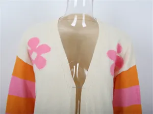Dettaglio del cardigan in maglia bianco con fiori rosa e maniche a righe arancioni