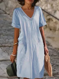 Detail of light blue cotton linen V-neck dress featuring lace trim and front pockets