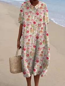 Zomerse maxi-jurk met bloemenprint en Peter Pan-kraag getoond op het zonnige strand