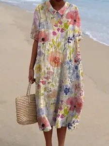 Detailopname van het kleurrijke bloemenpatroon op een loszittende zomerse maxi-jurk aan zee.