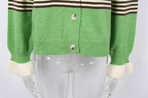 Vue détaillée d'un gilet en tricot rayé vert montrant les boutons et la texture côtelée.