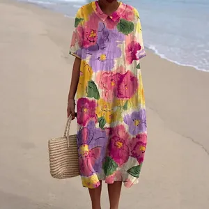 Detail van een kleurrijke maxi-jurk met bloemenprint en Peter Pan-kraag op een zandstrand