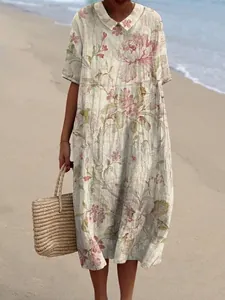 Een vrouw draagt een casual maxi-jurk met bloemenprint en Peter Pan-kraag op het strand
