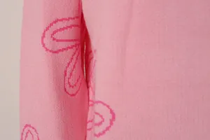 Close-up detail of the pink knit sweater showing the soft texture and floral pattern