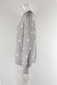 Detail side view of a gray knit pullover sweater featuring white polka dots on a mannequin