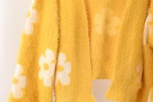 Primer plano de la textura suave de una chaqueta de punto amarilla con patrones florales