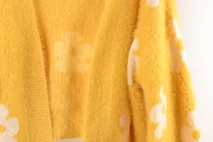 Primer plano detallado de cárdigan de punto amarillo con estampado floral blanco