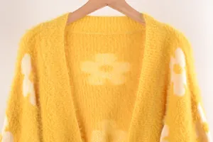Detalle en primer plano de la textura suave de un cárdigan amarillo con flores
