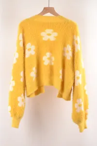Detalle de una chaqueta de punto suave de color amarillo con flores blancas