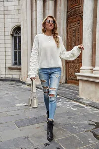 Detailed view of white chunky knit sweater with unique bobble texture sleeves and crew neck