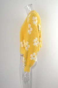 Perfil lateral de una chaqueta de punto amarilla con grandes motivos de flores blancas