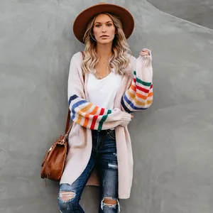 Détail du cardigan en maille à rayures arc-en-ciel avec jean déchiré et chapeau chic.