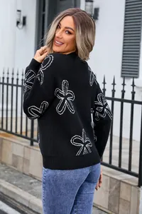 Detail view of women's black round neck knit sweater featuring a white floral pattern