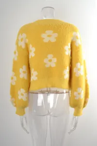 Vista trasera de un jersey corto de punto amarillo con grandes motivos florales blancos.
