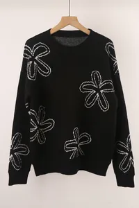 Close-up of black long-sleeved sweater featuring white knit flower pattern detailing