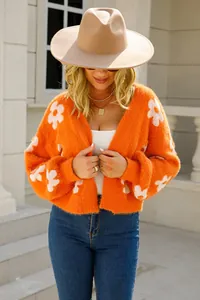 Primer plano detallado de un cárdigan naranja de punto suave con flores blancas