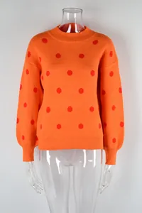 Detailed view of orange knit sweater with red polka dots on transparent mannequin
