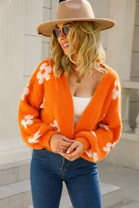 Vista detallada de la chaqueta de punto naranja con delicados motivos florales blancos