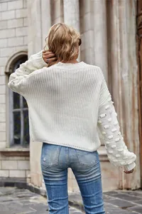 Back view of a white chunky knit sweater with textured bobble sleeves and cropped fit.
