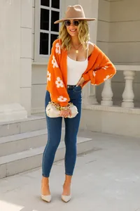 Mujer con cárdigan naranja de flores y vaqueros azules en escaleras exteriores
