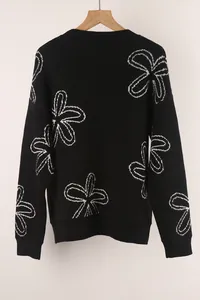 Detailed view of women's black long sleeve knit sweater with white floral bow patterns