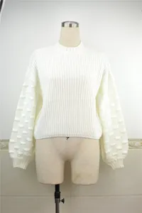 Close-up detail of white long sleeve knitted sweater with textured bubble sleeves.