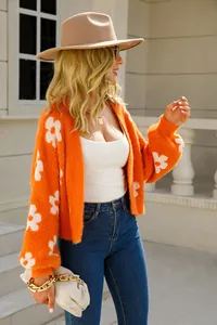 Vista detallada de un cárdigan de punto naranja con flores, textura suave para el otoño.