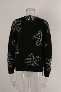 Detail shot of black long-sleeved crew neck sweater featuring white flower patterns